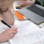 Estudante inclinada sobre um caderno fazendo anotações