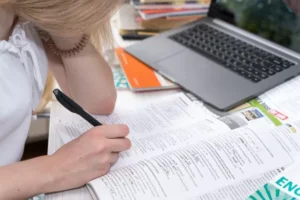 Estudante inclinada sobre um caderno fazendo anotações
